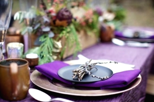 a bright purple Thanksgiving tablescape with a purple tablecloth and napkins, greenery and purple blooms is a stylish idea for a woodland Thanksgiving party