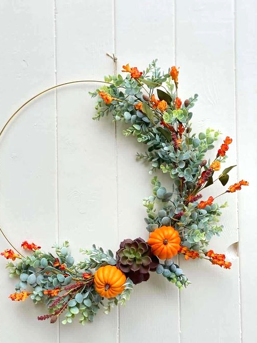 a bright fall or Thanksgiving wreath partly decorated with faux greenery, bold orange blooms, mini gourds and a succulent is chic