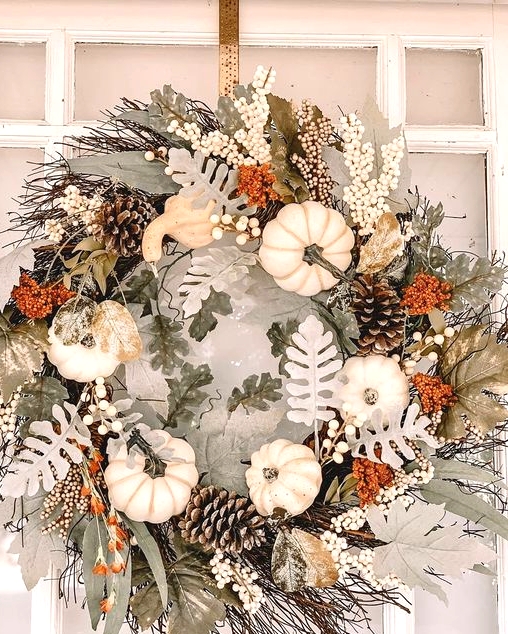 a pretty neutral textural fall or Thanksgiving wreath of pale leaves, white pumpkins, pinecones and twigs is a lovely idea