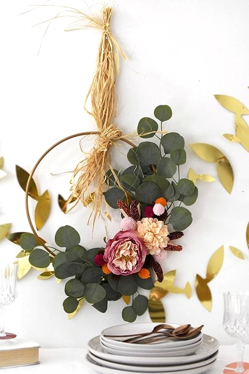 a refined and cute boho Thanksgiving wreath with greenery, pink and blush blooms and some hay is a cool idea to try