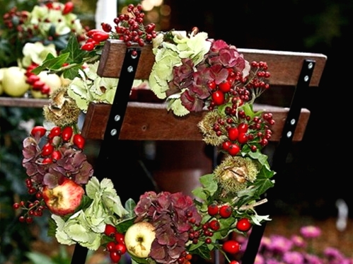 a fall or Thanksgiving wreath of greenery, berries, apples and dark blooms is a chic and very holiday-embracing idea