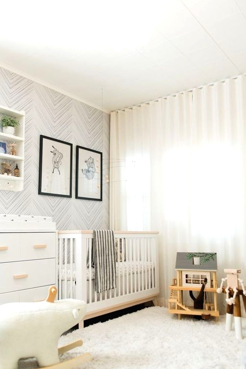 a neutral nursery with white and stained furniture, an open shelving unit, a wallpaper accent wall and some lovely and simple toys