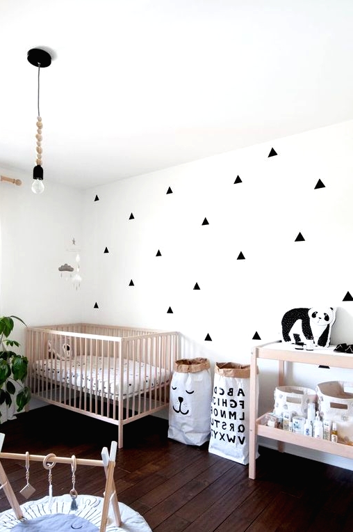 a stylish Nordic nursery with an accent wall, stained furniture, a pendant bulb, some toys and a potted plant is a lovely space