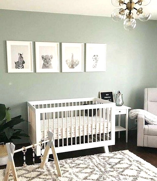 a soothing Scandi nursery with pale green walls, a white crib, a mini gallery wall, a potted plant, a neutral chair and a nightstand