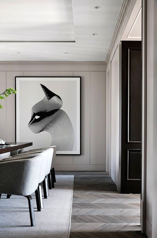 a chic greige dining room with a long dinign table, grey chairs, pendant lamps, a statement artwork and potted greenery
