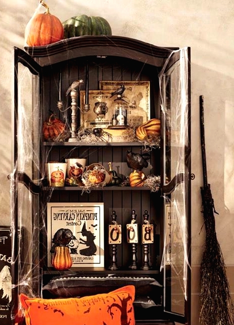 a vintage Halloween storage unit in black, with pumpkins, gourds, candles, signs and a broom by its side is a lovely idea for your party