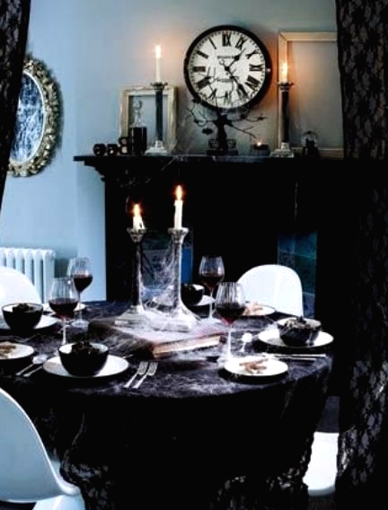 a refined vintage Halloween tablescape with a black tablecloth, white porcelain and black bowls, haunted candleholders with candles is amazing and chic
