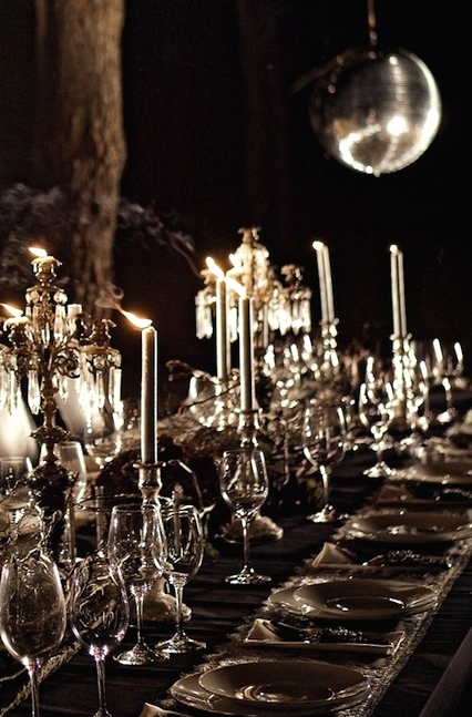 a refined haunted tablescape with a black tablecloth, white lace runners, white candleholders and candles, refined candelabras, dried blooms and greenery