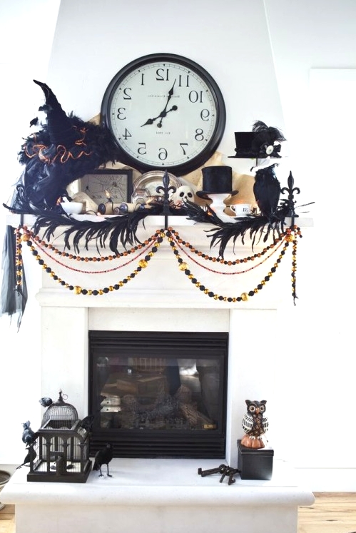 chic vintage Halloween mantel decor with feathers, blackbirds, buntings and garlands, witch hats and skulls is a bold and creative decor idea