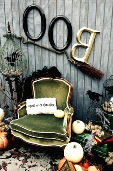 a vintage Halloween nook with a green vintage chair, stacks of vintage books, pumpkins, a broom and some letters