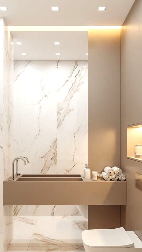 a contemporary and refined bathroom clad with white marble tiles, with a greige wall and a built-in sink plus built-in lights is cool