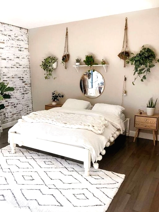 a lovely bedroom with a greige accent wall and a whitewashed brick one, a white bed with creamy bedding, stained nightstands and potted greenery