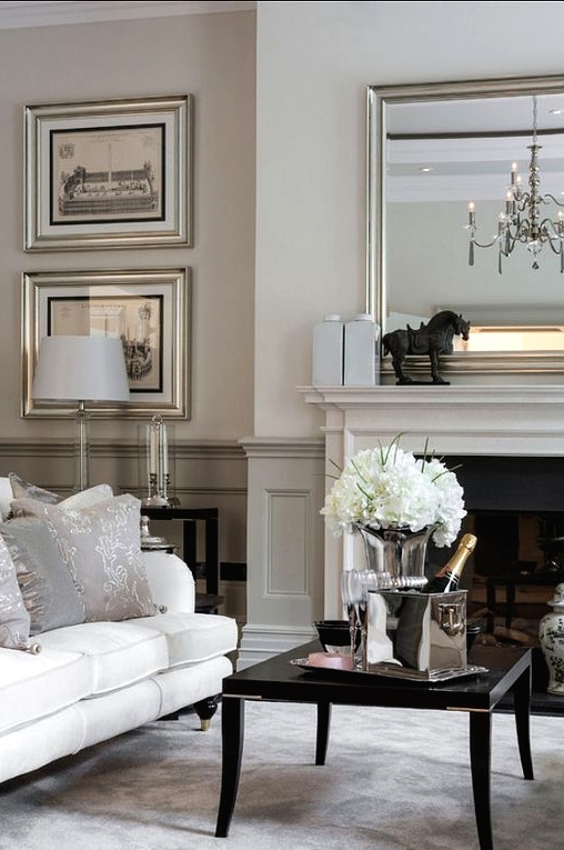a refined neutral living room with greige paneling, a built-in fireplace, a white sofa, a black coffee table and an elegant gallery wall