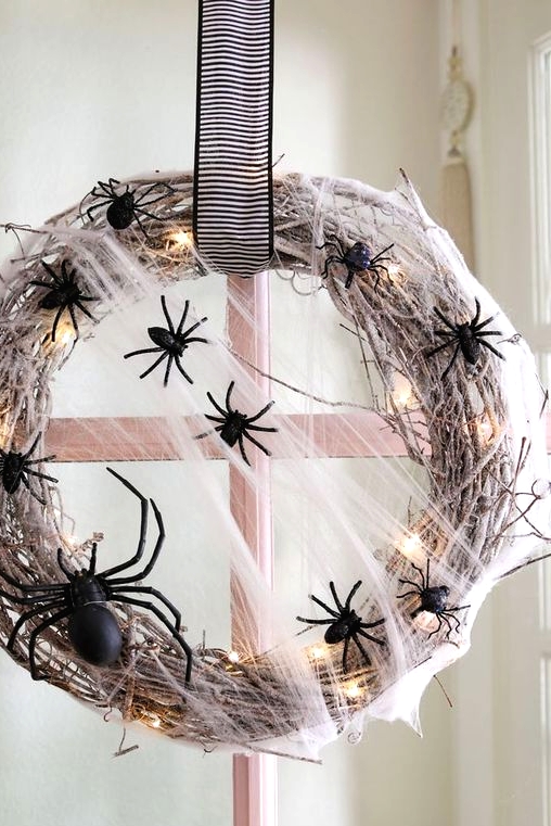 a bold and pretty Halloween wreath of whitewashed vine, LED lights, black spiders and a striped bow is a lovely idea to go for
