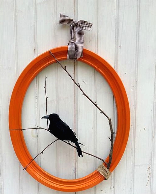 a bright and cool Halloween wreath of an orange picture frame, branches and a blackbird is a lovely and bold idea to rock