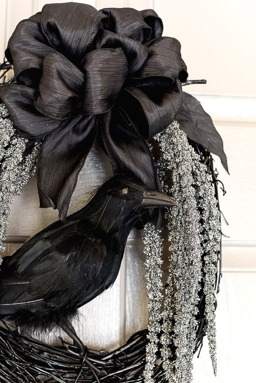 a refined Halloween wreath of black vine, hanging whitewashed blooms, a black black silk bow and a blackbird is classics for Halloween