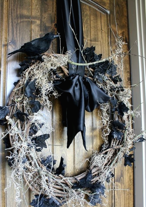 a shabby Halloween wreath of vine, hay, black leaves and a blackbird on top plus a black silk bow is amazing