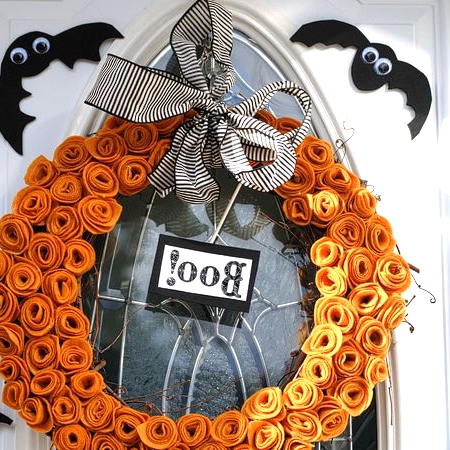 a bright and cool Halloween wreath of orange fabric swirls shaping a pumpkin, a striped bow, a sign and some faux bats around is amazing