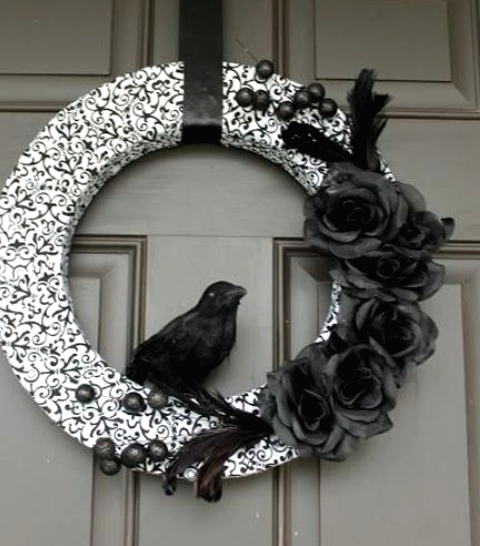 a black and white Halloween wreath with a printed form, black faux blooms and berries and a faux blackbird is a gorgeous idea