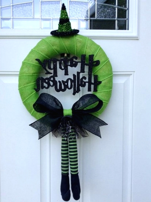 a bold green Halloween wreath with glitter letters, a bow and long witch legs plus a witch hat on top is a fun and cool idea