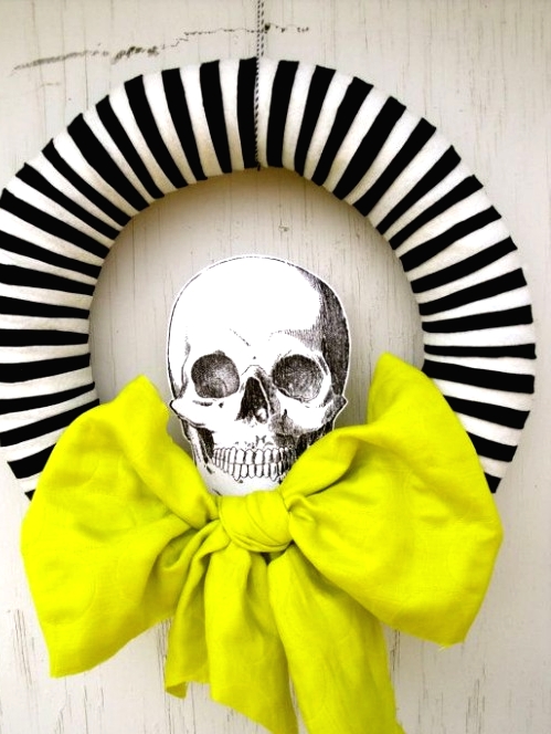 a modern Halloween wreath with a striped form, a neon green bow and a printed skull is a lovely and easy to DIY idea