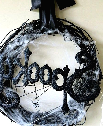 a bold black Halloween wreath of vine, with shiny and sparkly letters, spider net and a large bow on top is a stylish and cool idea