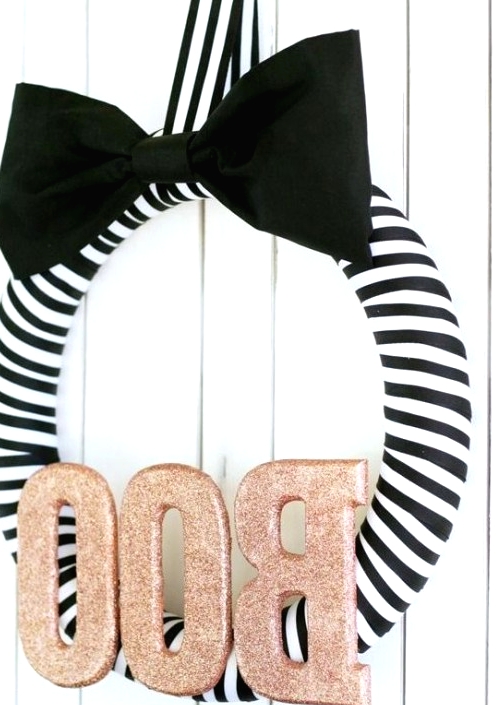 a glam Halloween wreath of a striped form, a large black bow and copper glitter letters is a gorgeous solution