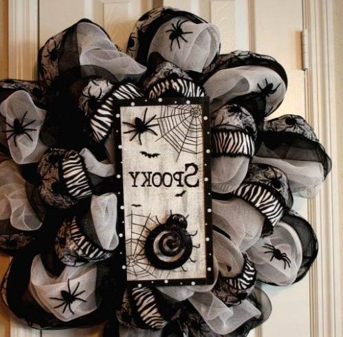 a whimsy black and white Halloween wreath covered with fabric and ribbons, with spiders and a sign with spider nets and spiders is a unique solution for decor