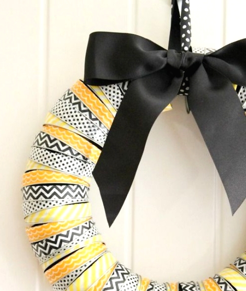 a bright Halloween wreath covered with printed black, white and yellow ribbons and a large black bow on top is a gorgeous idea