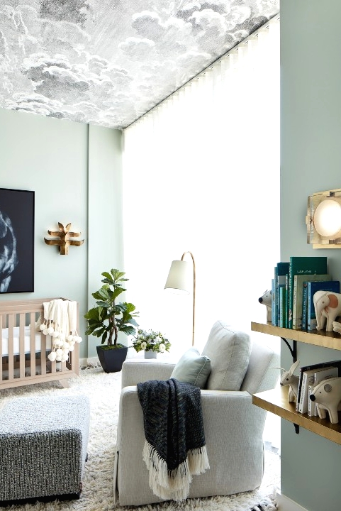 a contemporary ligth green nursery with a cloud ceiling, a neutral crib, a neutral chair with a footrest, floating shelves and potted plants