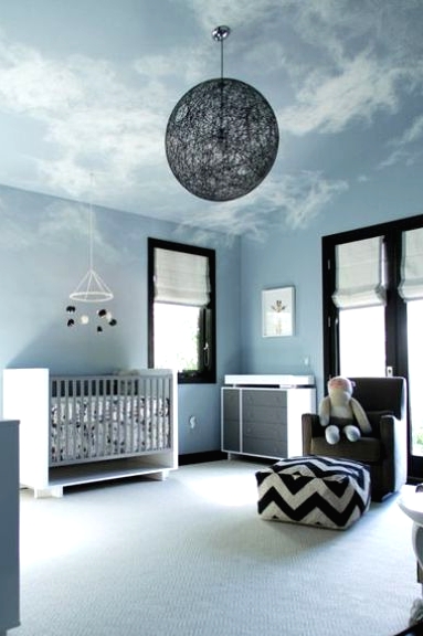 a contemporary sky blue nursery with a neutral crib and changing table, a grey chair and a printed ottoman plus a yarn ball lamp