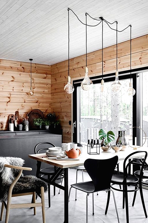 a cozy Scandinavian dining space with a sleek dining table, mismatching chairs, pendant bulbs and a candleholder