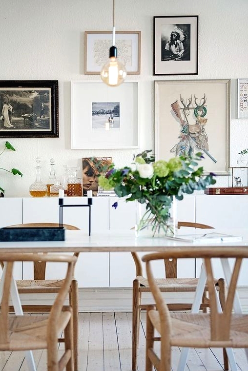 a Nordic dining zone with a white table, woven chairs, a gallery wall and a sleek white credenza plus potted plants