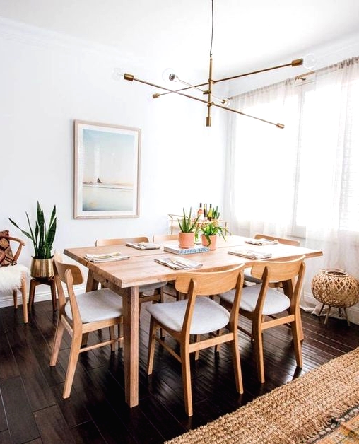 a pretty modern Scandinavian dining space with a stained table and neutral chairs, a dreamy artwork, a cool chandelier and faux fur