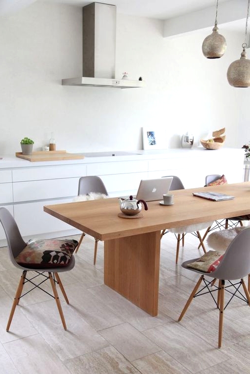a sleek Nordic dining room with a light-stained table and matching grey chairs plus metal pendant lamps