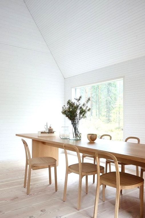 an airy Scandinavian dining space with a stained table and chairs, with a view of the forest is a lovely idea