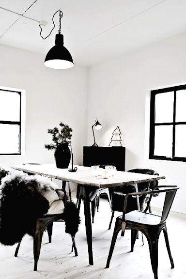 a contrasting Nordic dining room with a wood and metal dining table, blakc metal chairs, a black metal pendant lamp and some black furniture in the corner