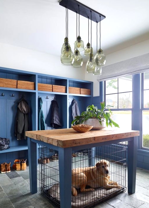 a farmhouse entryway with a blue clothes rack with seats, blue walls and a matching dog kennel with a butcherblock countertop