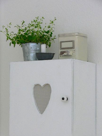 a small whitewashed cabient with a cutout heart is a pretty solution for a Scandinavian or shabby chic space and it looks amazingly cute