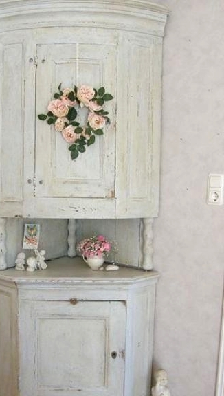 a vintage whitewashed corner cabinet of two parts connected with each other and with pink blooms is a lovely idea