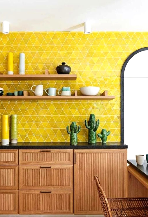 a light-stained kitchen with black countertops, open shelves and a super bold yellow triangle backsplash and bold accessories