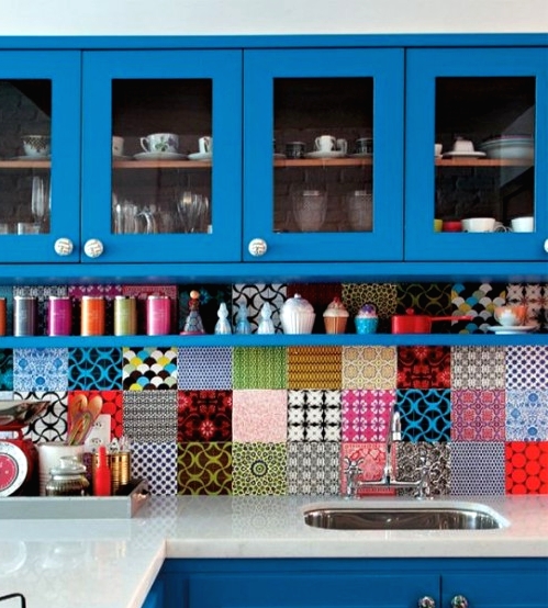 a bold blue kitchen with a super colorful mismatching tile backsplash and colorful accessories to support the colors of the backsplash