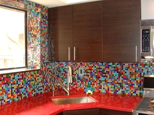a rich-stained kitchen with bold red countertops and a colorful mosaic tile backsplash and walls that accents the space and makes it non-boring