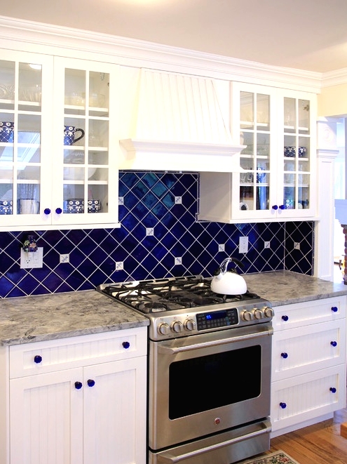 a wihte kitchen with shaker cabinets, grey countertops, a bold navy tile backsplash clad with a geometric pattern and matching glass knobs is a cool idea