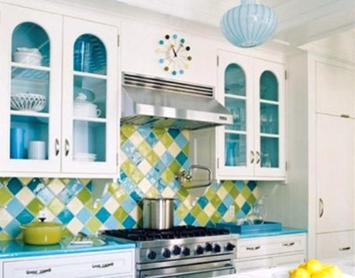 a white kitchen with shaker cabinets, with glazed cabinets, blue countertops and a green and blue geometric tile backsplash is a fun and bold idea