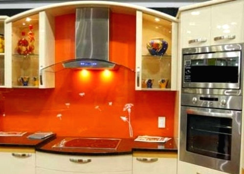 a neutral kitchen with an orange glass backsplash and built-in appliances is a lovely idea of a cheerful space