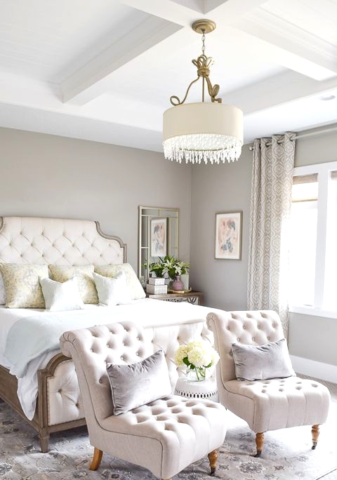 a beautiful and sophisticated greige bedroom with creamy upholstered furniture, neutral pillows, pritned curtains and a rug, a pendant lamp with crystals and mirrors