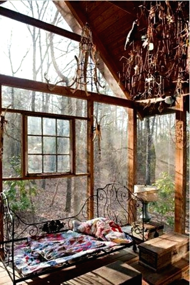 a shabby chic boho sunroom with a view of the forest, a forged bed, wooden chests and vintage chandeliers is a quirky space
