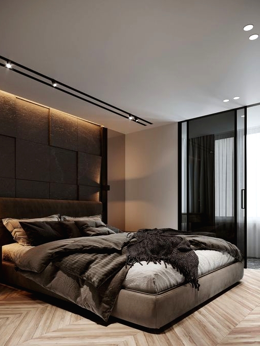 a stylish and refine dmodern bedroom with a taupe accent wall, a taupe upholstered bed with matching bedding, built-in lights and glass sliding doors