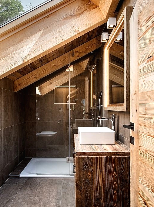 an attic chalet bathroom with a skylight, large scale tiles, a floating vanity, wooden beams and walls is amazing